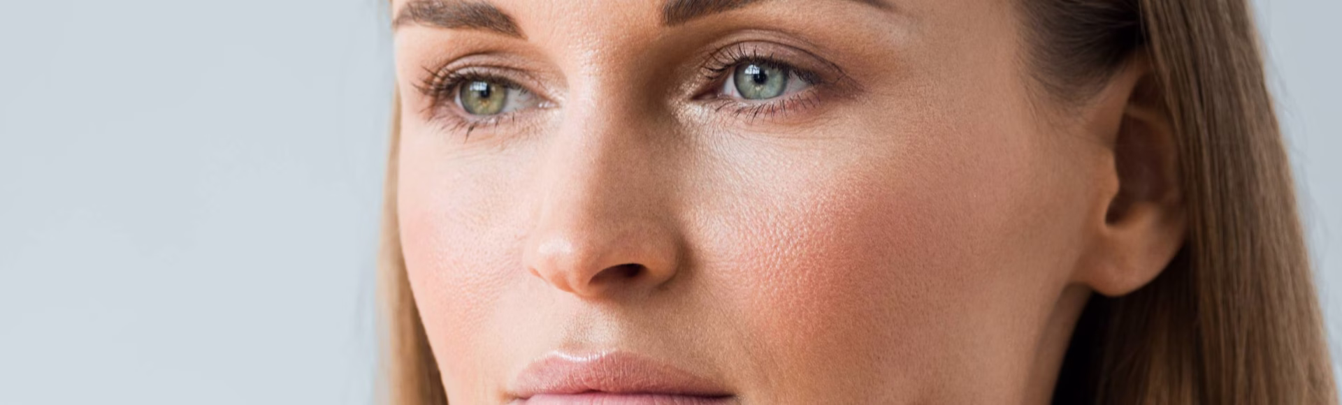 Biorevitalización facial: primer plano de una mujer de ojos verdes con la piel del rostro hidratada y luminosa
