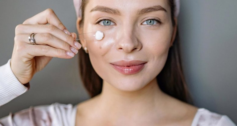 Mujer sonriente de piel luminosa con un toque de crema en la mejilla