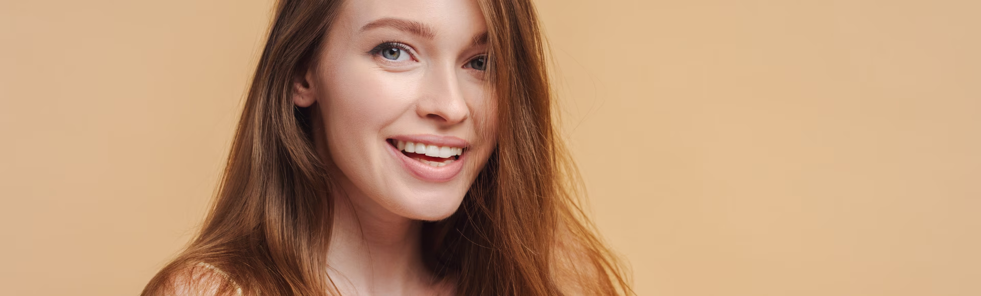 Mujer sonriente con el pelo largo sobre fondo beige